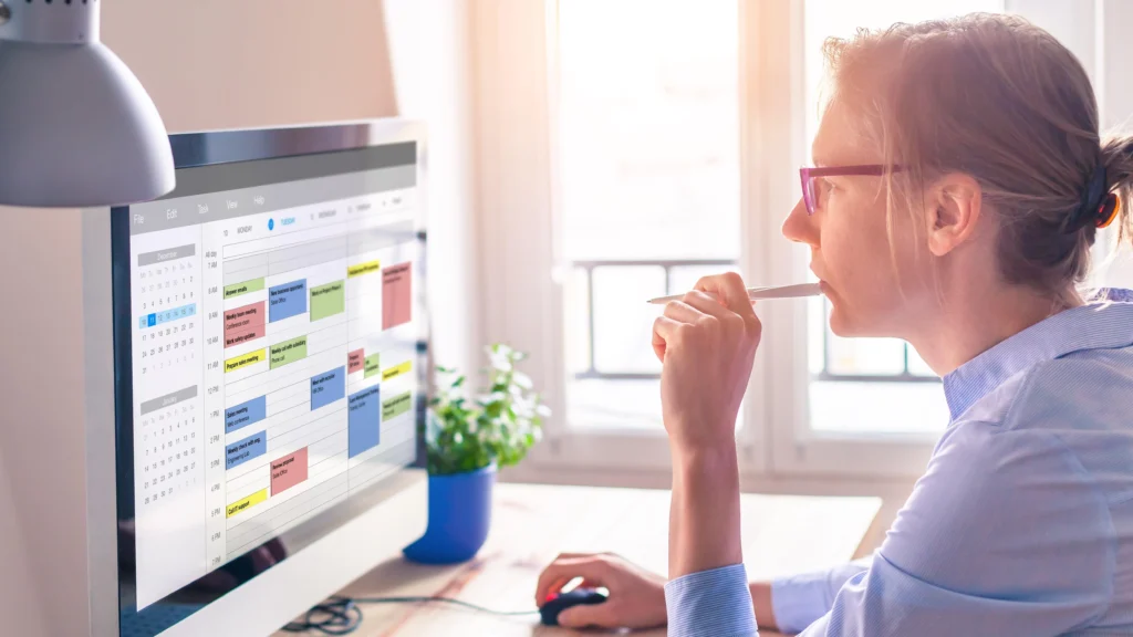 Employee managing work schedule with digital calendar and productivity software